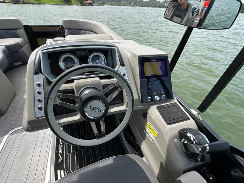 Slide: The Image of 2023 Barletta Corsa 23UC boat dashboard with steering wheel and control panel on a lake. - 24