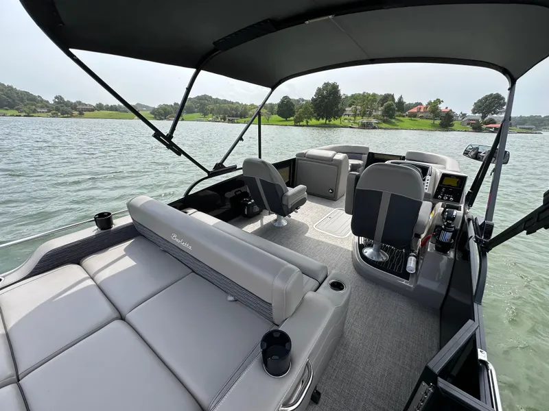Slide: The Image of 2023 Barletta Corsa 23UC pontoon boat interior with seating and helm on a lake. - 28