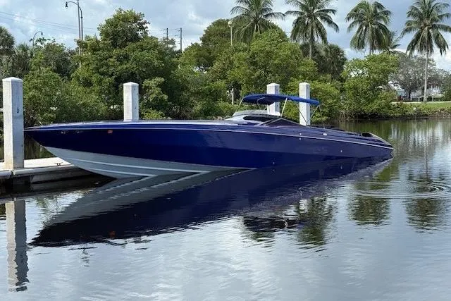 The Image of 2007 Nor-Tech 5000V powerboat docked on calm water with lush greenery and palm trees. - 1