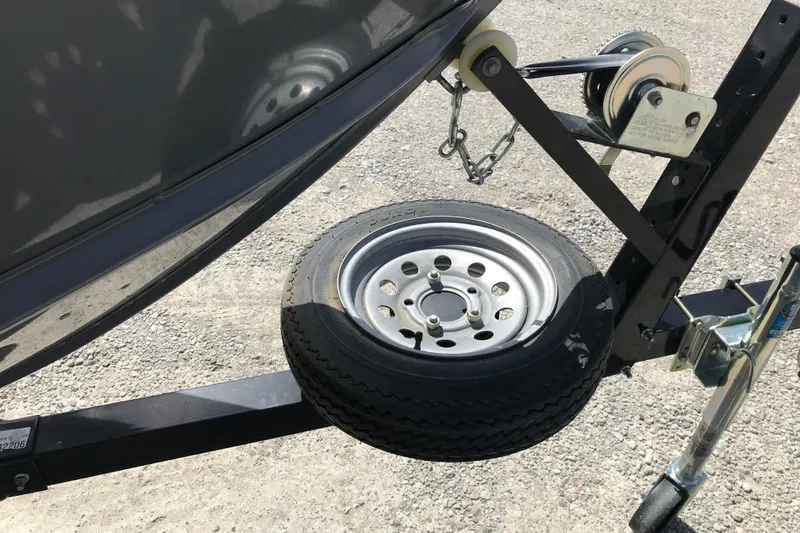 Slide: The Image of Trailer hitch and spare tire for 2007 Lund 1425 Classic Tiller boat on gravel surface. - 7