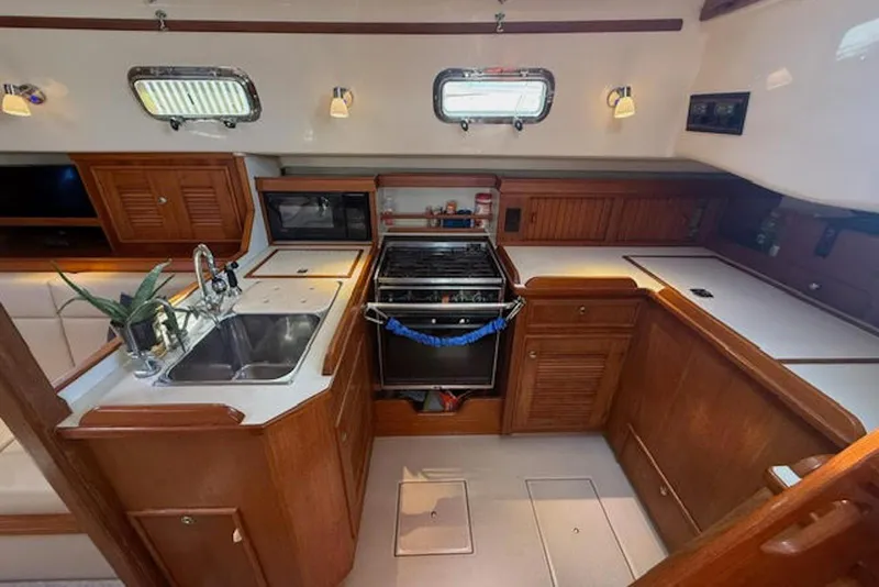Slide: The Image of 2001 Island Packet 380 yacht kitchen with wooden cabinetry, stove, and dual sink. - 33