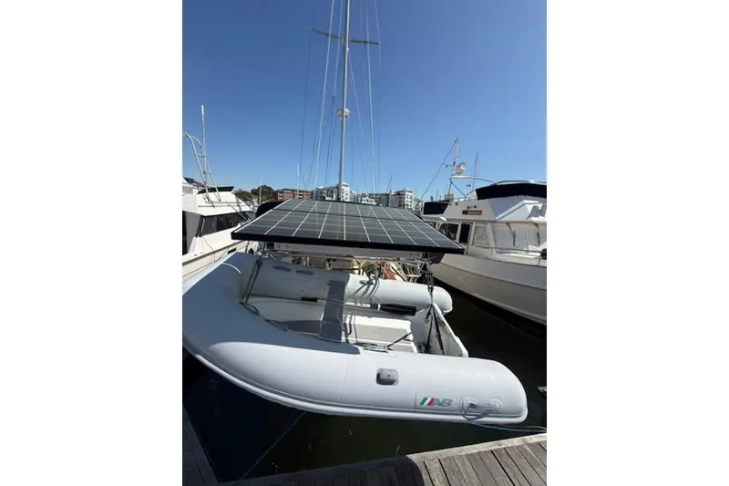 Slide: The Image of Sailboat Island Packet 380 (2001) docked, featuring solar panels and inflatable dinghy. - 48