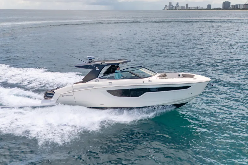 Slide: The Image of 2021 Cruisers Yachts 38 GLS speeding on open water, city skyline in background. - 14