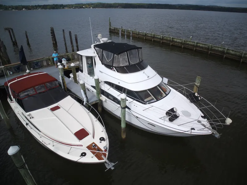 Slide: The Image of Two yachts are docked. The 2003 Carver 44 Cockpit Motor Yacht is white with a black canopy. - 3