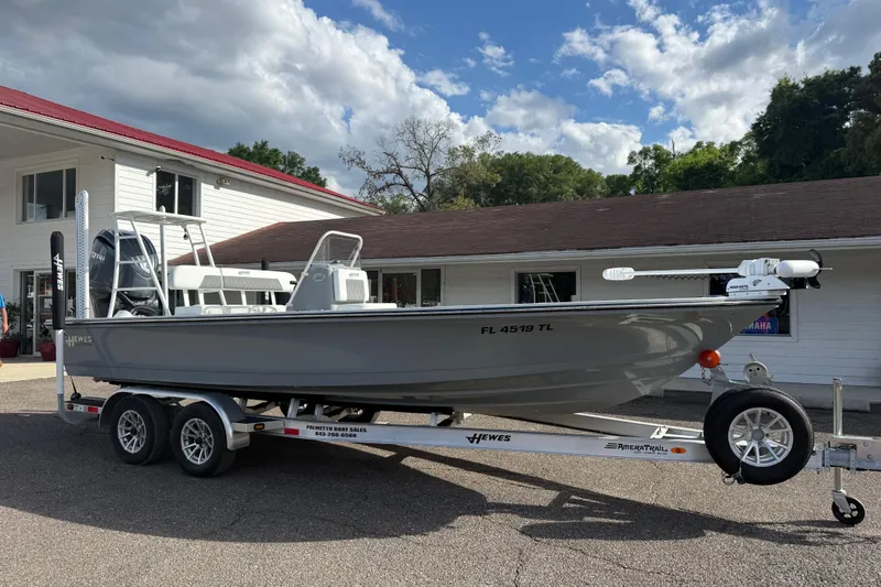 Slide: The Image of 2023 Hewes Redfisher 21 boat on trailer, parked outside a building under a cloudy sky. - 3
