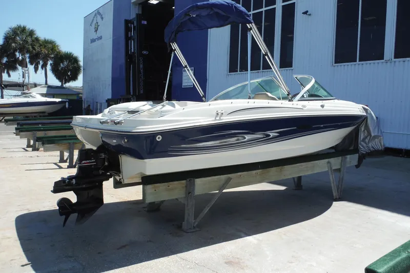 Slide: The Image of 2004 Sea Ray 180 Sport boat on display at a marina with palm trees. - 2