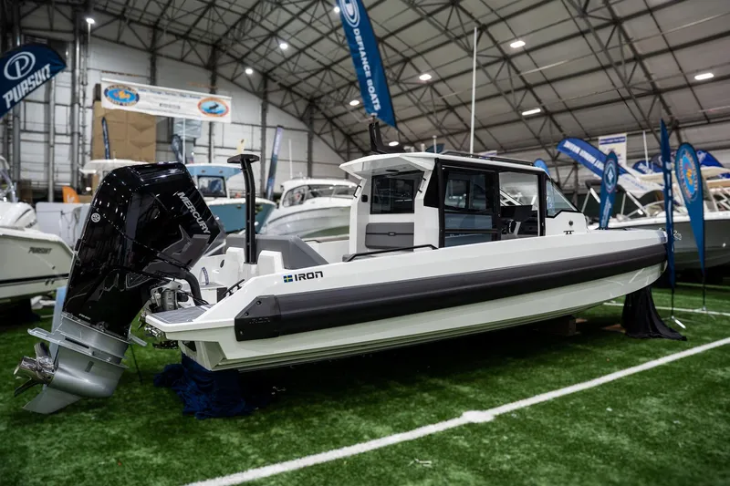 Slide: The Image of 2026 Iron 907 Coupe boat displayed indoors with Mercury engine, surrounded by other boats. - 3