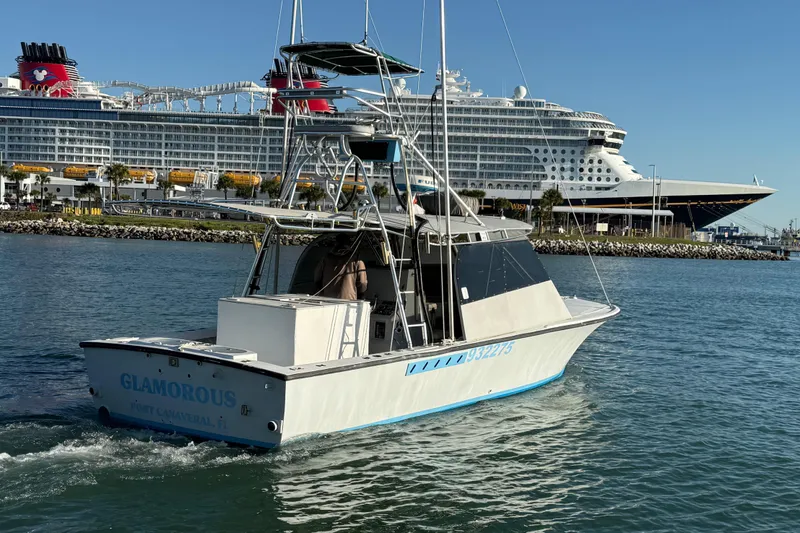 Slide: The Image of 1988 Stuart Angler 32 boat named "Glamorous" cruising near a large cruise ship. - 3