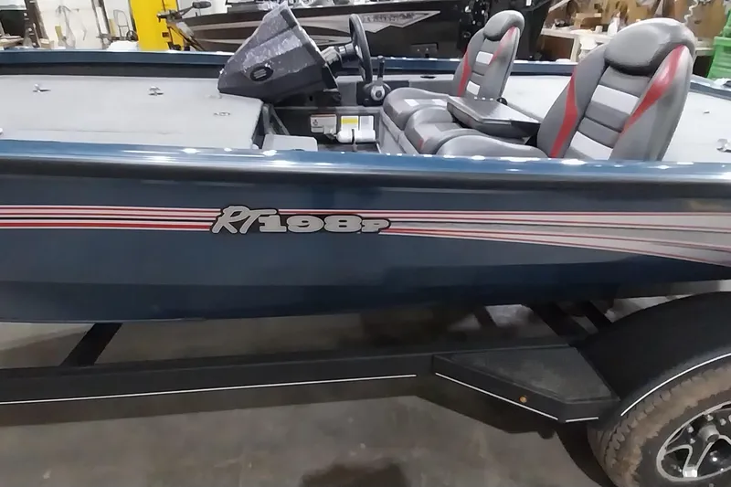 Slide: The Image of 2024 Ranger RT198P boat with dual seats and sleek design in a showroom. - 12