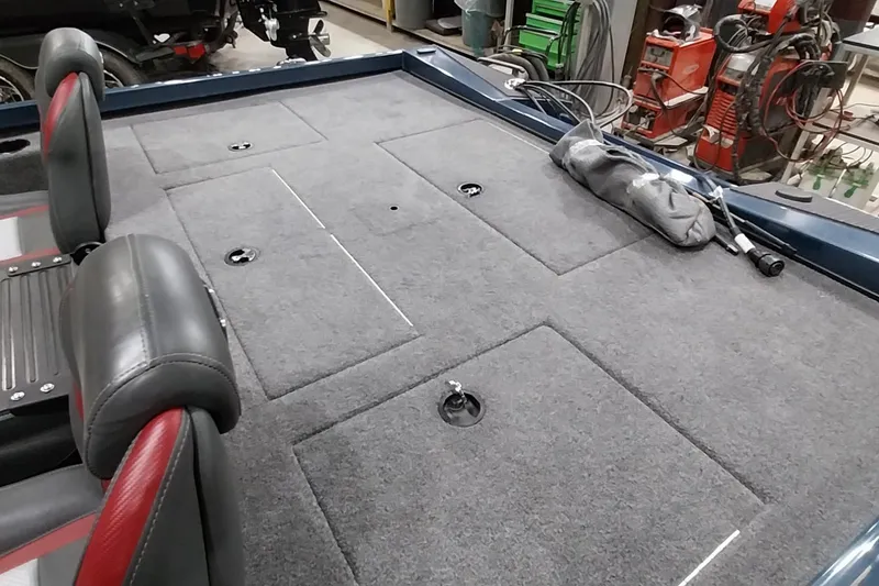 Slide: The Image of 2024 Ranger RT198P boat interior with carpeted deck and seating in a workshop. - 14