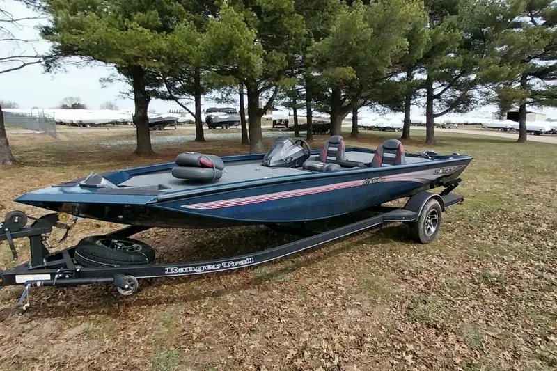 Slide: The Image of 2024 Ranger RT198P boat on trailer, parked on grass with trees in background. - 28