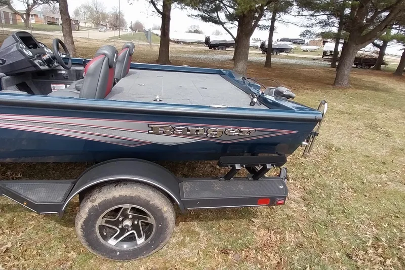 Slide: The Image of 2024 Ranger RT198P boat on trailer, parked on grass with trees in background. - 31