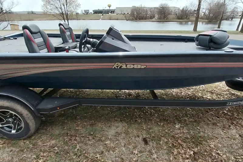 Slide: The Image of 2024 Ranger RT198P boat on trailer by a lake, showcasing sleek design and seating. - 34