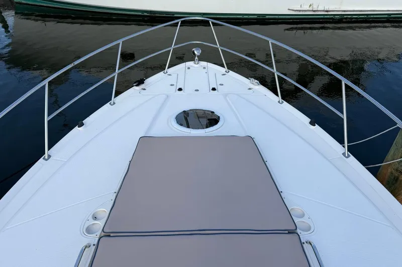 Slide: The Image of 2005 Regal Commodore 3860 boat deck with railing and sun pad, docked on calm water. - 12