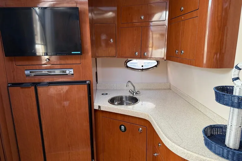 Slide: The Image of 2005 Regal Commodore 3860 yacht interior with kitchenette, TV, and wooden cabinetry. - 15