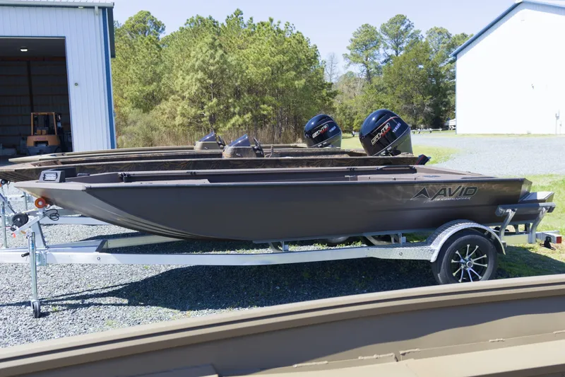 Slide: The Image of 2026 Avid 18 Commander boat on trailer, parked outdoors near a building. - 1