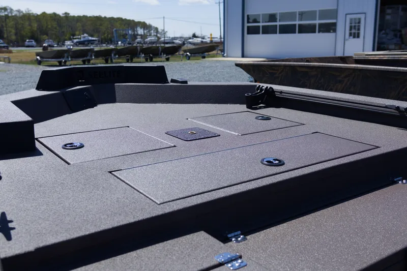 Slide: The Image of 2026 Avid 18 Commander boat deck with storage compartments, parked outdoors near other boats. - 6