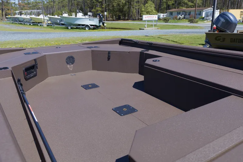 Slide: The Image of 2026 Avid 18 Commander boat interior with spacious deck and seating, parked outdoors. - 9
