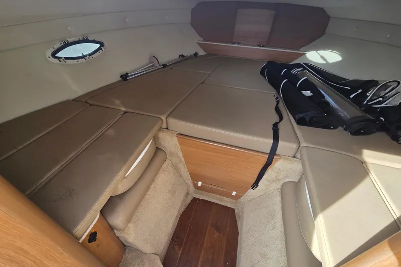 Slide: The Image of 2016 Rinker 236 Captiva Cuddy cabin interior with beige upholstery and storage space. - 14