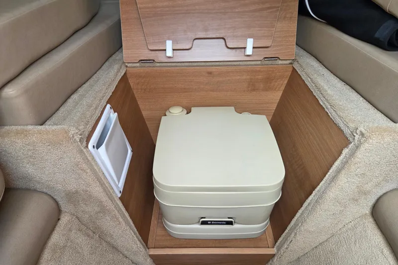 Slide: The Image of Portable toilet in 2016 Rinker 236 Captiva Cuddy cabin, featuring wood paneling and carpeted interior. - 16
