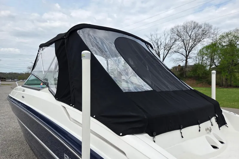 Slide: The Image of 2016 Rinker 236 Captiva Cuddy boat with black canopy, parked outdoors. - 19