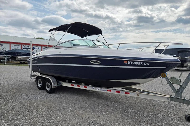 Slide: The Image of 2016 Rinker 236 Captiva Cuddy boat on trailer, parked outdoors under cloudy sky. - 2