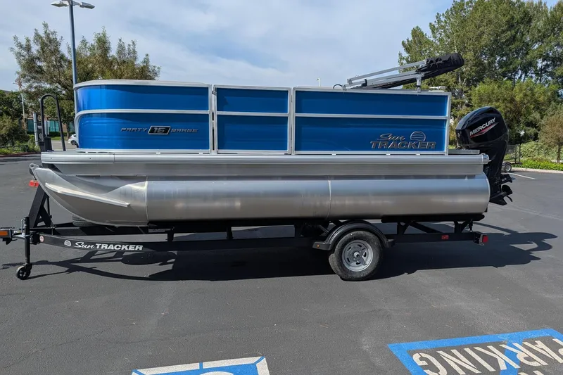 The Image of 2026 Sun Tracker Party Barge 16 DLX pontoon boat on trailer in parking lot. - 0