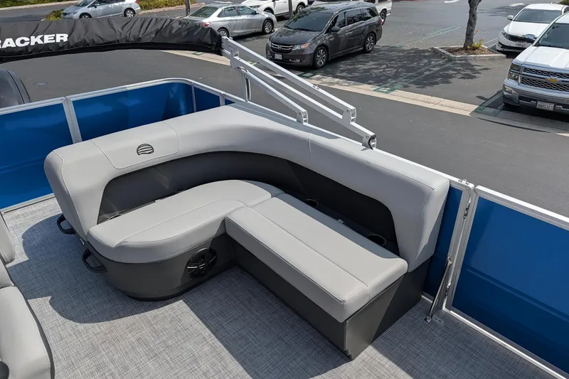 Slide: The Image of 2026 Sun Tracker Party Barge 18 DLX with gray seating and blue railing in a parking lot. - 7
