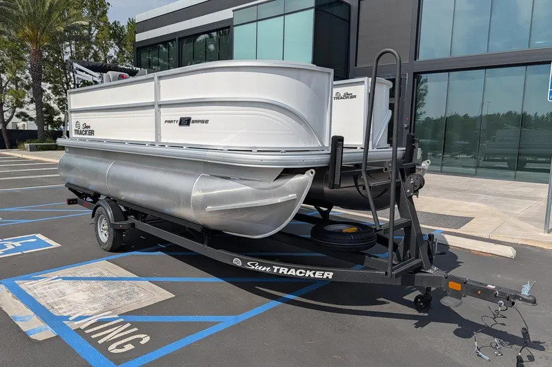 Slide: The Image of 2026 Sun Tracker Party Barge 16 DLX pontoon boat on trailer in parking lot. - 3