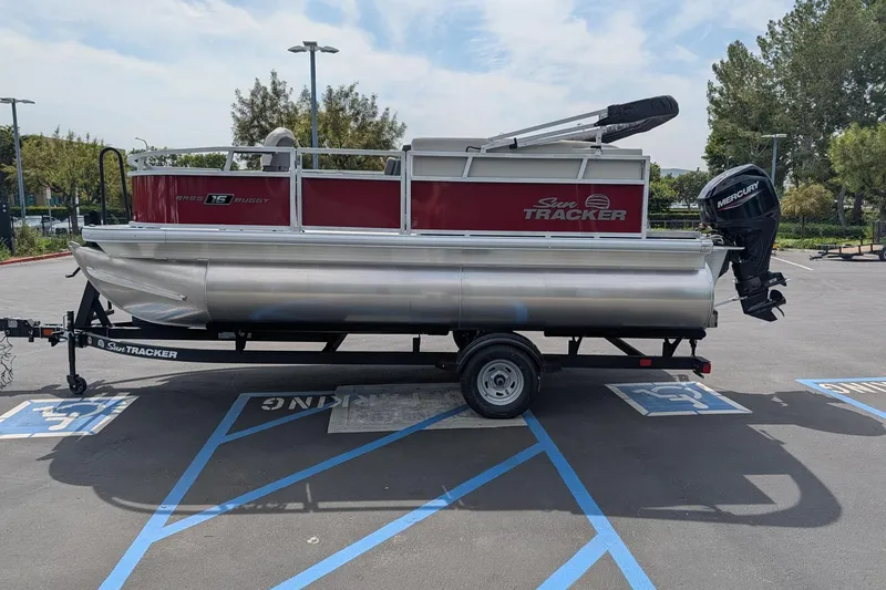 The Image of 2026 Sun Tracker Bass Buggy 16 XL Select pontoon boat on trailer in parking lot. - 0