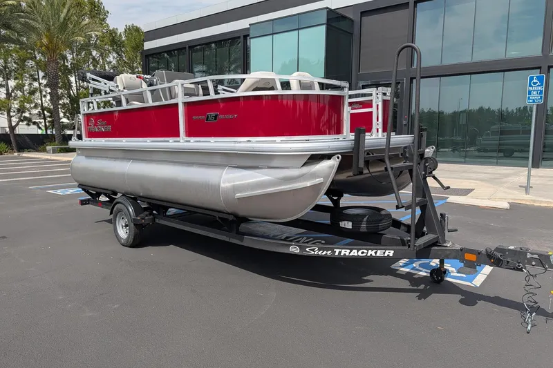 Slide: The Image of 2026 Sun Tracker Bass Buggy 16 XL Select pontoon boat on trailer in parking lot. - 3
