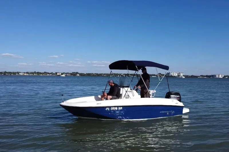 Slide: The Image of 2018 Bayliner Element F16 boat on calm water under clear blue sky. - 20