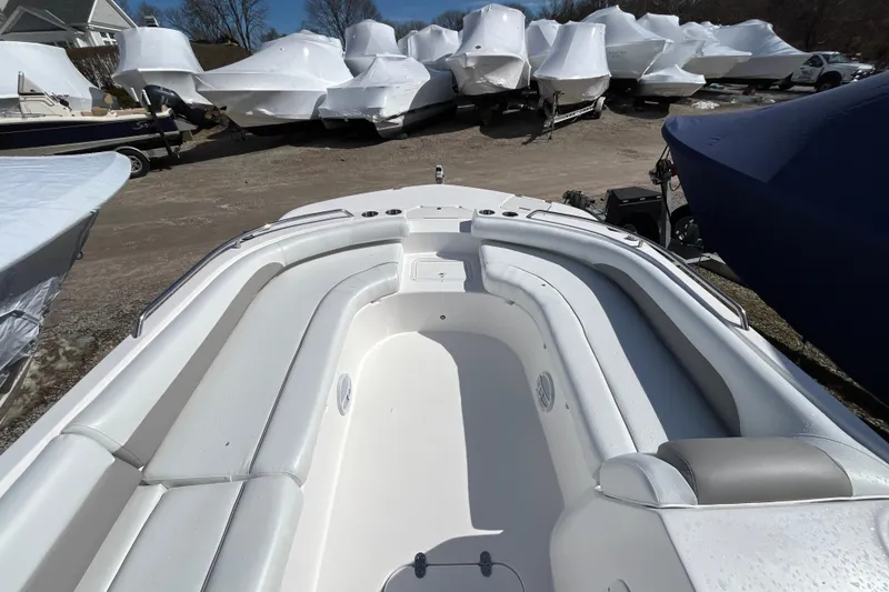 Slide: The Image of 2015 Hurricane SunDeck Sport 201 OB boat interior with white seating, parked among covered boats. - 11
