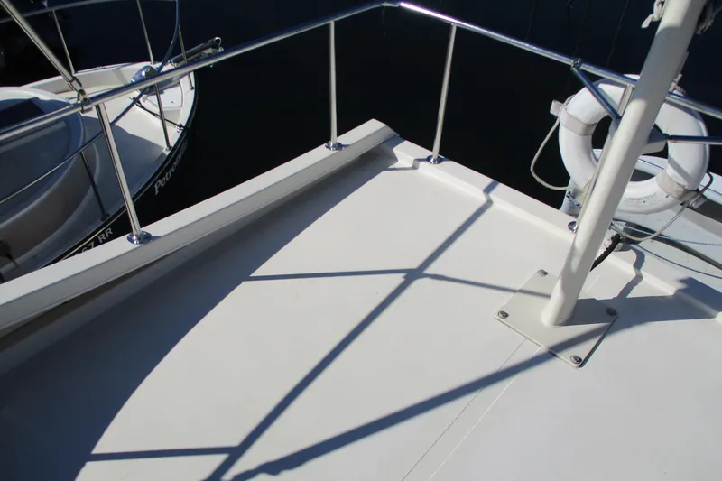 Slide: The Image of 2005 Camano Troll Flybridge deck with railing and lifebuoy, docked beside another boat. - 11