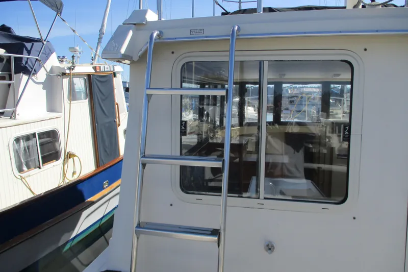 Slide: The Image of 2005 Camano Troll Flybridge boat with ladder and window, docked at marina. - 13