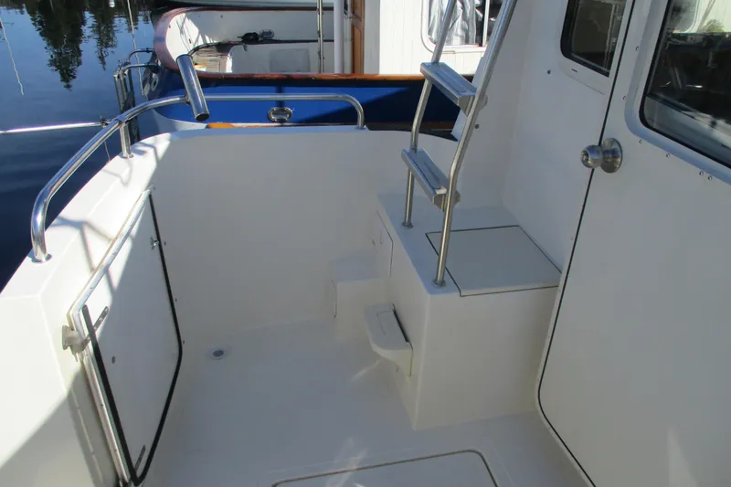 Slide: The Image of 2005 Camano Troll Flybridge boat deck with ladder and railing, docked by water. - 15