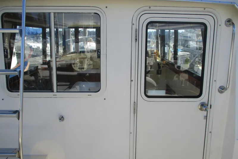 Slide: The Image of 2005 Camano Troll Flybridge boat exterior with windows and door, docked at marina. - 16