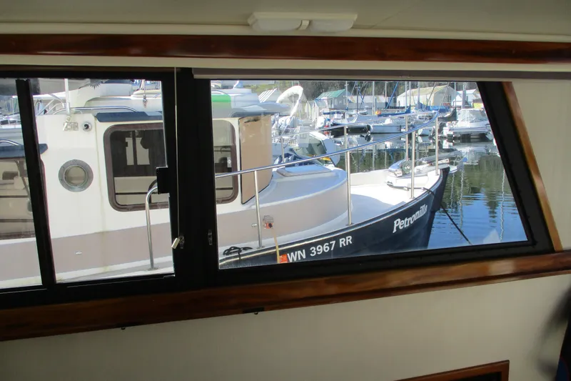 Slide: The Image of 2005 Camano Troll Flybridge boat viewed through a window at a marina. - 25