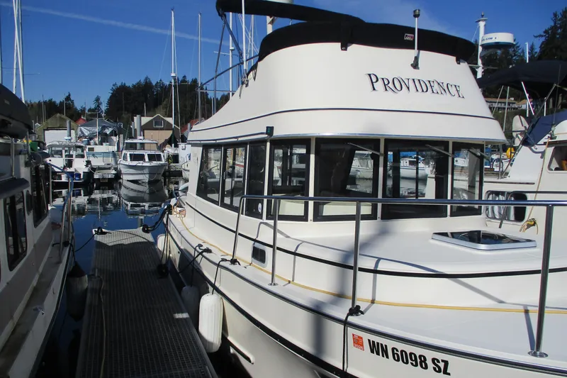 Slide: The Image of 2005 Camano Troll Flybridge boat docked in a marina, featuring sleek design and spacious deck. - 2