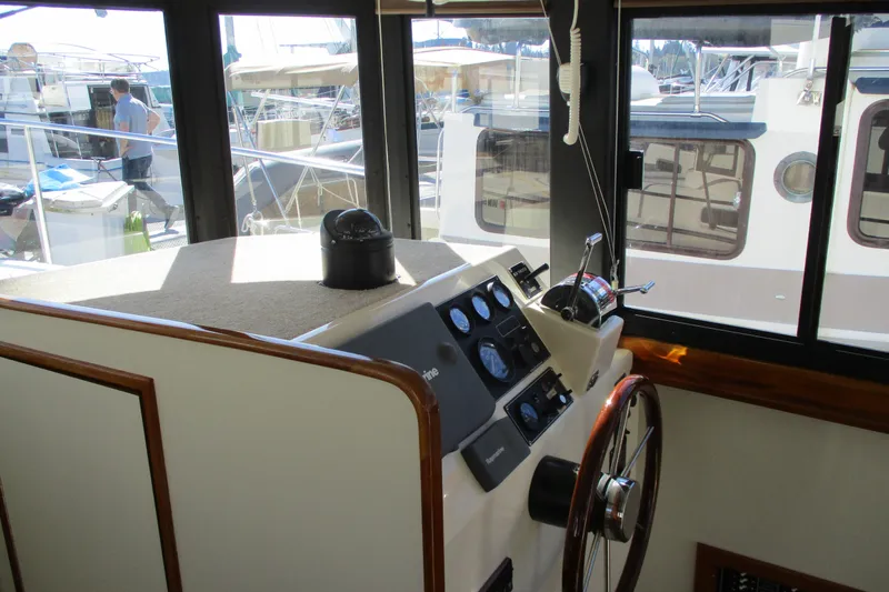 Slide: The Image of 2005 Camano Troll Flybridge helm with steering wheel and control panel, docked at marina. - 21
