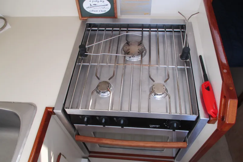 Slide: The Image of Compact kitchen stove on 2005 Camano Troll Flybridge boat, featuring three burners and oven. - 34
