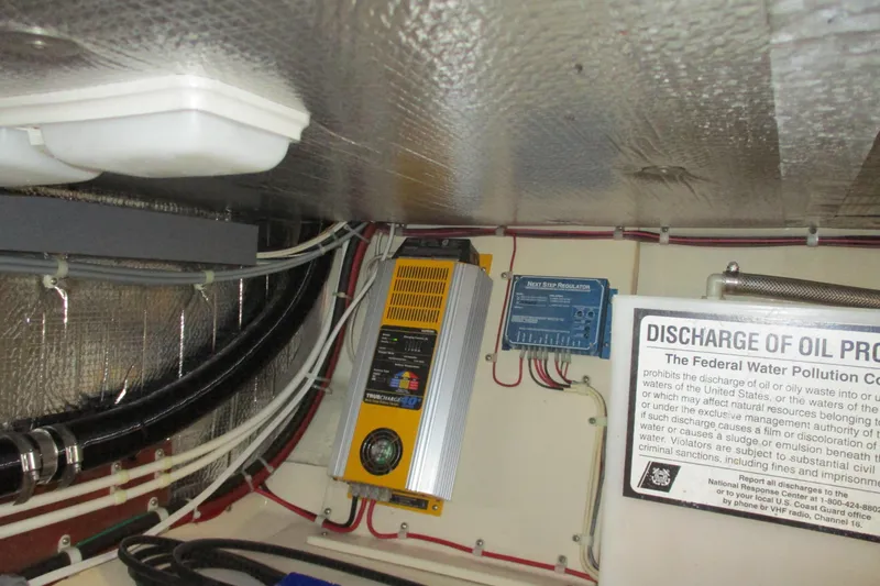 Slide: The Image of Engine room of 2005 Camano Troll Flybridge with electrical components and oil discharge warning sign. - 49
