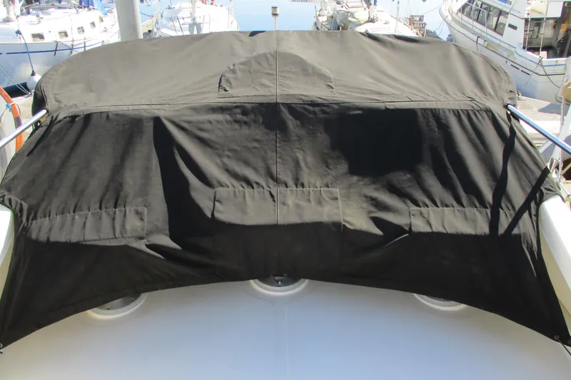 Slide: The Image of 2005 Camano Troll Flybridge with black cover, docked at marina. - 6