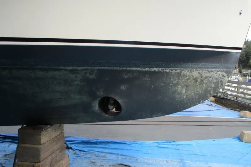 Slide: The Image of 2005 Camano Troll Flybridge boat hull on blocks, showing propeller and marine growth. - 63