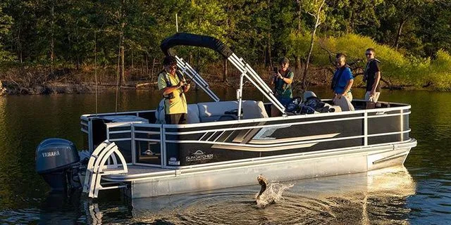 Slide: The Image of SunCatcher Select 20F 2026 pontoon boat on a serene lake with anglers. - 16
