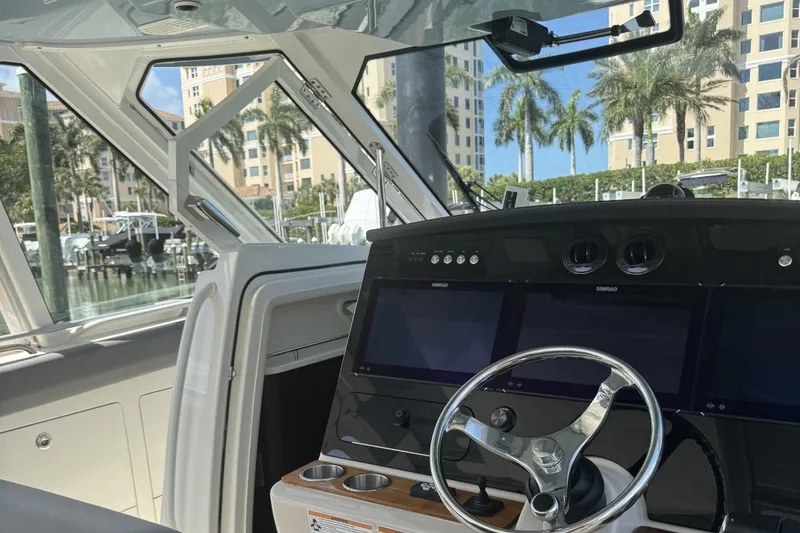 Slide: The Image of 2024 Boston Whaler 380 Realm helm with modern navigation displays and steering wheel. - 12