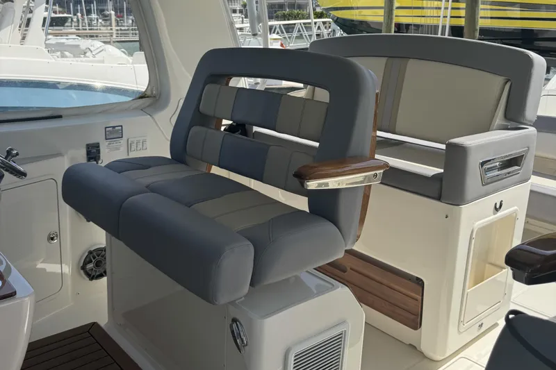 Slide: The Image of 2024 Boston Whaler 380 Realm interior seating with luxurious gray upholstery and wooden accents. - 8