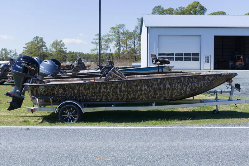 The Image of Avid 20 Rogue SC 2026 boat on trailer, parked near a garage. - 0