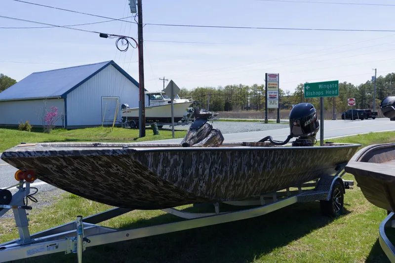 Slide: The Image of 2026 Avid 20 Rogue SC boat on trailer, parked near road signs and building. - 2