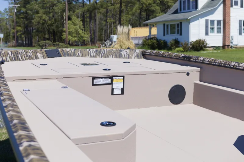 Slide: The Image of 2026 Avid 20 Rogue SC boat interior with camouflage trim, parked near a house. - 9